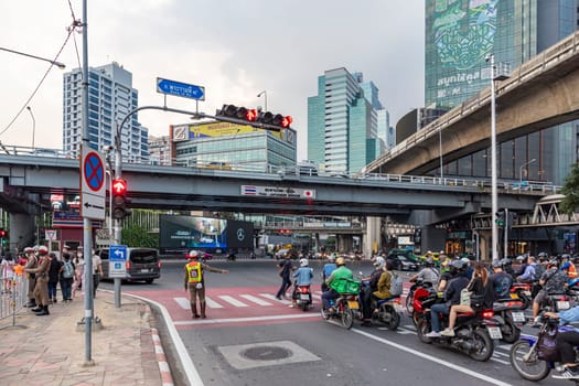 Bangkok, Thailand - Dec 8, 2022 : The traffic police are working at the Sala Daeng intersection. On Rama IV Road, which is one of the most congested roads. There are both sky train and subway train