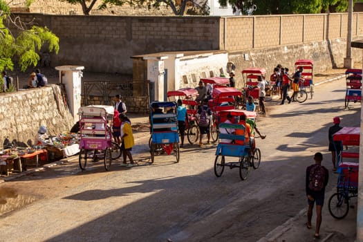 Toliara, Madagascar - November 21. 2022: Traditional rickshaw bicycle with Malagasy passengers on the street, one of the ways to earn money. Everyday life on the cities street of Madagascar.
