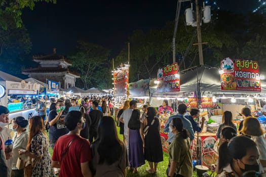 Bangkok, Thailand - Dec 8, 2022: Many people walk to get food from good restaurants. Many to choose from at the Red Cross Fair at night at Lumpini Park from December 8-18, 2022. Motion blur.