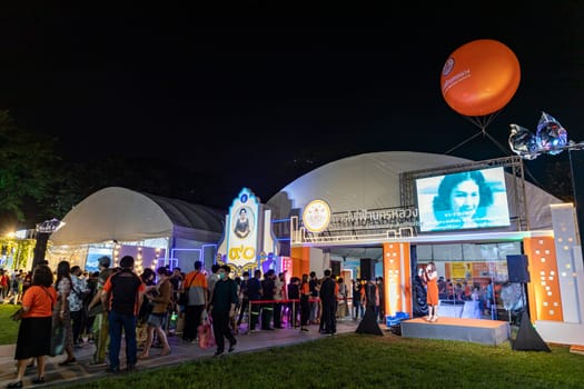 Bangkok, Thailand - Dec 8, 2022 : Many people queue up to watch the exhibition of state-owned enterprises in the Red Cross Fair at Lumpini Park at night. Between 8-18 December 2022, motion blur