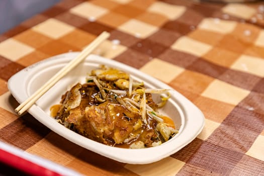 Hoy-Tod Delicious Thai food made from oysters, flour, egg and fried until crispy. Famous Thai food. Put in a disposable paper plate on a table covered with plastic checkered cloth. Selective focus.