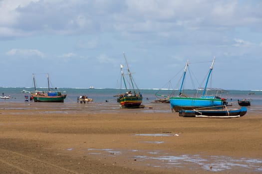 Toliara, Madagascar - November 21st 2022: Fishing boat stranded on the dry port during low tide with Malagasy people around.