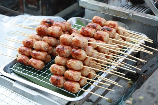 Isaan Sausage, a very popular street food in Thailand. Easy to buy, cheap price, delicious taste made from pork stuffed with sour seasoned rice and pork, served with ginger, fresh chilli, and lettuce.