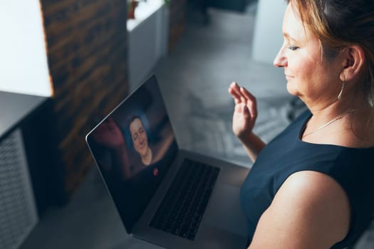 Woman having business video call on laptop in office. Mature busy woman remotely working from office. Female manager using digital devices. Remote communication. Video calling. Remote work