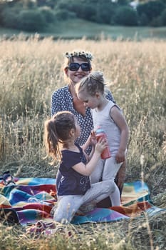 Family spending time together on a meadow, close to nature. Parents and children playing together, making coronet of wild flowers. Candid people, real moments, authentic situations