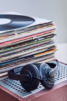 Stack of many black vinyl records, headphones put on the top of vinyls. Copy space for text. Candid people, real moments, authentic situations