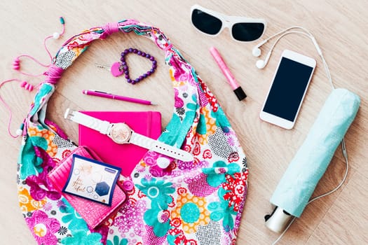 Smartphone sunglasses wallet notebook and other things pulled out of handbag put on a table