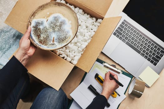 Business owner packing online order to delivery to customer. Preparing parcel box with ceramic plate product from online shop