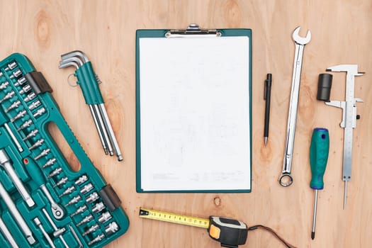 Workshop table with many tools. Wrench, spanner, calliper and ratchet with many attachments. Clipboard with white paper. Work tools. Universal tool set. Professional equipment. Background. Copy space