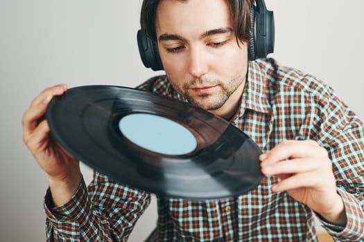 Man listening to music from vinyl record. Playing music from analog disk on turntable player. Enjoying music from old collection. Relaxing at home. Retro and vintage. Music passion