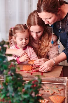 Family decorating baked Christmas gingerbread cookies with frosting