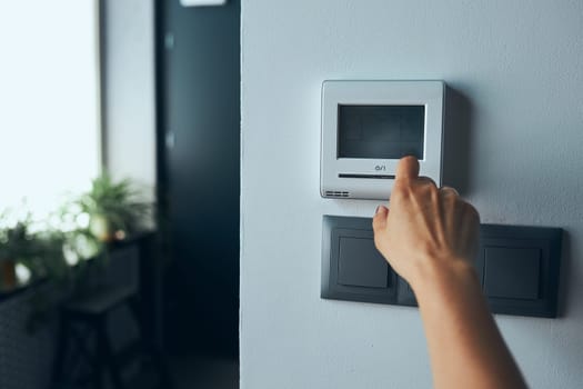 Woman controlling office with digital touch screen panel installed on the wall in office. Concept of smart remote control. Managing system at work. Woman using digital device to activate lock system at smart office