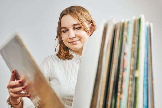 Playing vinyl records. Listening to music from vinyl record player. Retro and vintage music style. Young woman searching analog LP record album in stack of old records. Music collection. Music passion