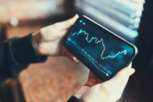Person investing trading on stock cryptocurrency market using investing application on smartphone. Stock market investment in hand. Trader holding mobile phone looking at candle chart