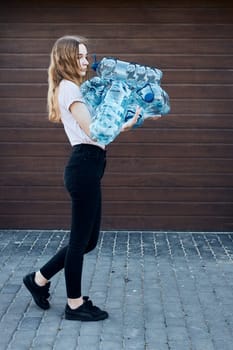 Young woman throwing out empty used plastic water bottles into trash bin. Collecting plastic waste to recycling. Concept of plastic pollution and too many plastic waste. Environmental issue