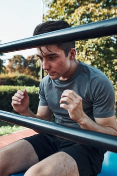 Young man doing sit-ups during his workout in a modern calisthenics street workout park. Man sitting on a sit-up board wearing sportswear
