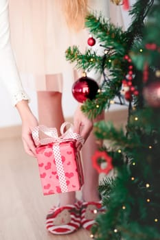 Closeup of girl getting Christmas gift from under a tree