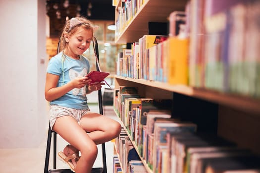 Schoolgirl looking for book in school library. Student choosing book for reading. Books on shelves in bookstore. Learning from books. Back to school. Elementary education. Doing homework
