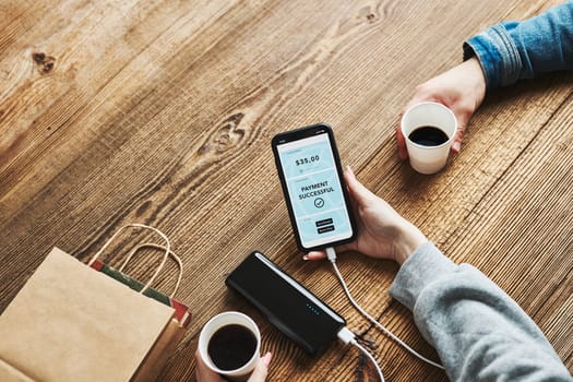 Online shopping. Paying online. Ordering product in online shop using smartphone. Payment confirmation on screen. Online banking. Paying for online shopping while charging mobile phone from powerbank in coffee shop