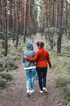 Mother and her little daughter walking in a forest during summer vacation trip. Family spending time together outdoors in nature