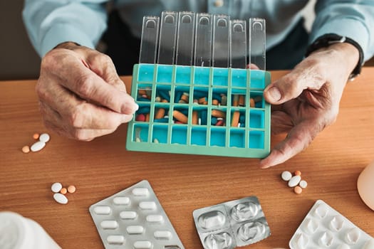 Senior man organizing his medication into pill dispenser. Senior man taking pills from box. Healthcare and old age concept with medicines. Medicaments on table