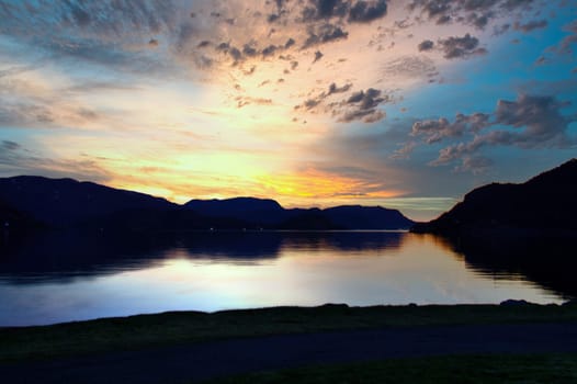 Fjord with sunset and illuminated clouds in the sky. View of mountains and fjord landscape in Norway. Landscape shot in the evening in the north