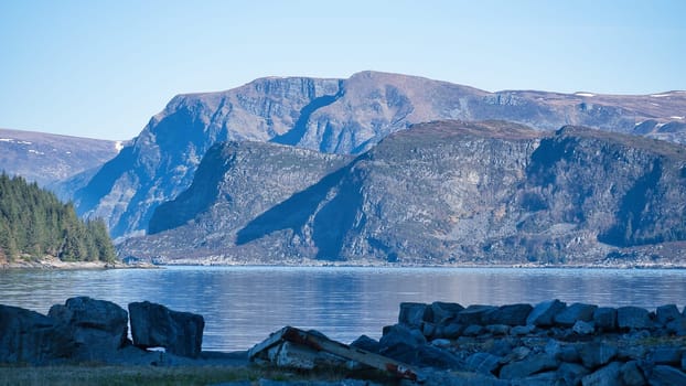 View across the fjord to the West Cape in Norway. The sun shines on the water and makes it glisten. Landscape photo from Scandinavia