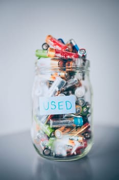 Jar filled with discharged used batteries. Waste disposal and recycling. Separating the waste. Batteries only container