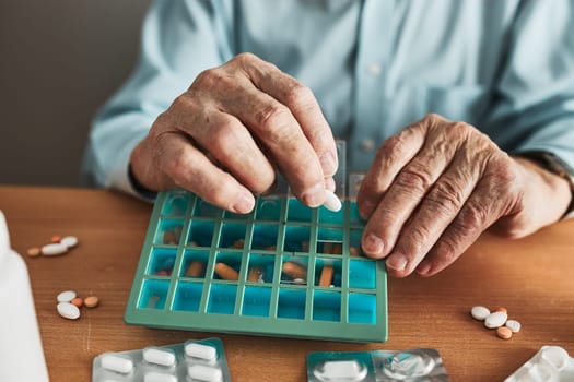 Senior man organizing his medication into pill dispenser. Senior man taking pills from box. Healthcare and old age concept with medicines. Medicaments on table