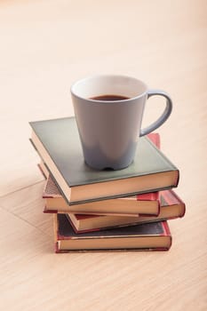 A few books with cup of coffee on wooden floor