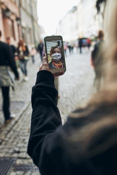 Young woman having video call talking while walking downtown in the evening wearing the face mask to avoid virus infection and to prevent the spread of disease in time of coronavirus