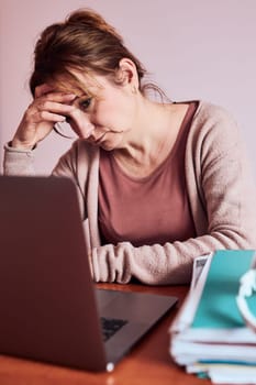 Woman focused on her work working hard doing her job remotely on laptop from home. Woman sitting at desk in front of computer looking at screen. Concept of remote working