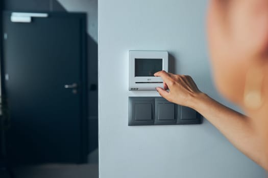 Woman controlling office with digital touch screen panel installed on the wall in office. Concept of smart remote control. Managing system at work. Woman using digital device to activate lock system at smart office