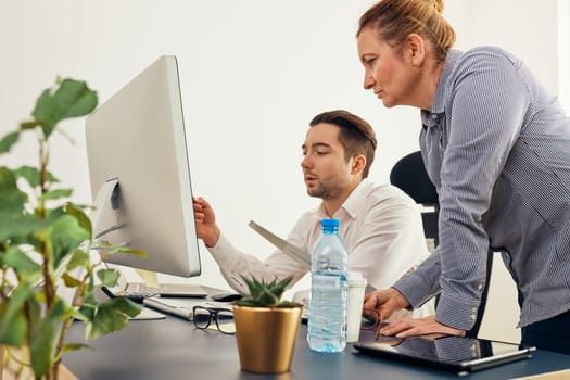 Business colleagues discussing financial data working together in office. People entrepreneurs working with charts and tables on computer. Two people working together. Workmates talking about project