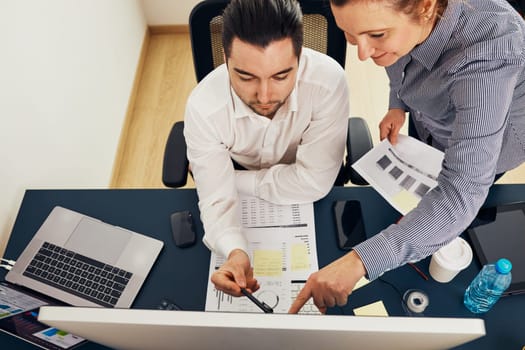 Business colleagues discussing financial data working together in office. People entrepreneurs working with charts and tables on computer. Two people working together. Workmates talking about project
