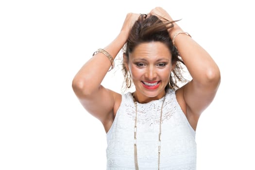 Portrait of a young brunette woman with her hands in her hair joyfully laughing isolated against a white background