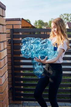 Young woman throwing out empty used plastic water bottles into trash bin. Collecting plastic waste to recycling. Concept of plastic pollution and too many plastic waste. Environmental issue