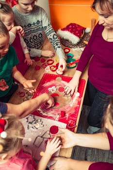 Baking Christmas cookies. Christmas gingerbread cookies in many shapes decorated with colorful frosting, sprinkle, icing, chocolate coating, toppers, put on table. Baking traditional cookies. Family celebrating Christmas. Baking at home. Baked sweet cookies. Coating with frostings. Colouring cookies. Decorating baked cookies. Decoration and design of food. Flat top-down composition. Sweet dessert food. Putting a frost, frosting gingerbread. Shot from above