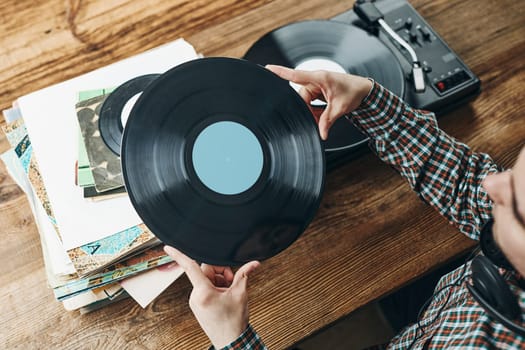 Man listening to music from vinyl record. Playing music from analog disk on turntable player. Enjoying music from old collection. Relaxing at home. Retro and vintage. Music passion