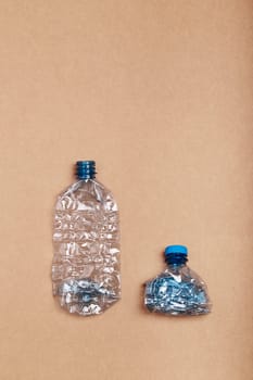 Squashed empty plastic bottles put in a row, over cardboard background. Collecting plastic waste to recycling. Concept of plastic pollution and too many plastic waste. Copy space for text