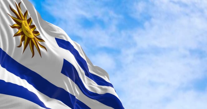 Uruguay national flag fluttering in the wind on a sunny day. 9 horizontal stripes: white and blue alternated, with Sol de Mayo in white square. 3d illustration render.