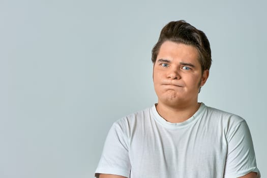 a frowning man on a gray background, copy space. High quality photo
