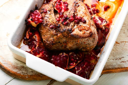 Piece of whole meat roasted with pomegranate seeds for Christmas in baking tray.