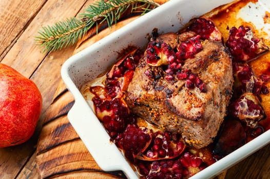 Fragrant piece of ham baked with pomegranate on old wooden table. Recipes meat for Christmas.Rustic style.