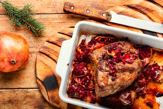 Fragrant piece of ham baked with pomegranate on old wooden table. Recipes meat for Christmas.Rustic style.