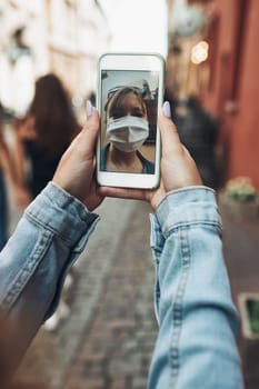 Young woman having video call talking while walking downtown chatting with friend wearing the face mask to avoid virus infection and to prevent the spread of disease in time of coronavirus