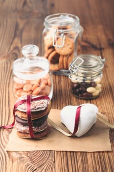 Gingerbread cookies, candies, cakes, sweets in jars on wooden table. Portrait orientation