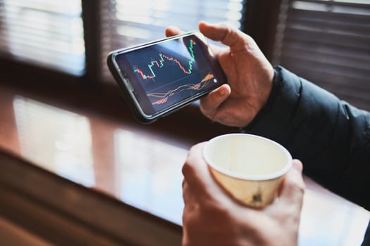 Person investing trading on stock cryptocurrency market using investing application on smartphone. Stock market investment in hand. Trader holding mobile phone looking at candle chart