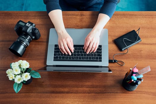 Female photographer working on photos on laptop and camera. Woman editing retouching browsing photos working as a freelancer sitting at desk
