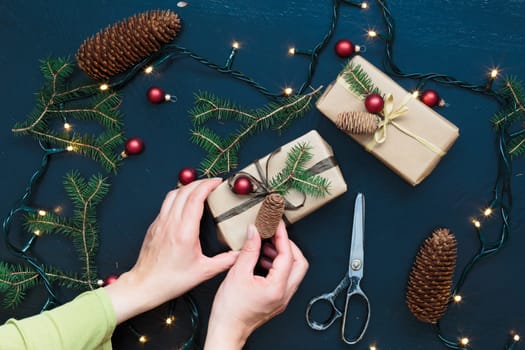 Wrapping the Christmas presents. Gifts wrapped in paper decorated with cones and pine twigs put on wooden table. View from above